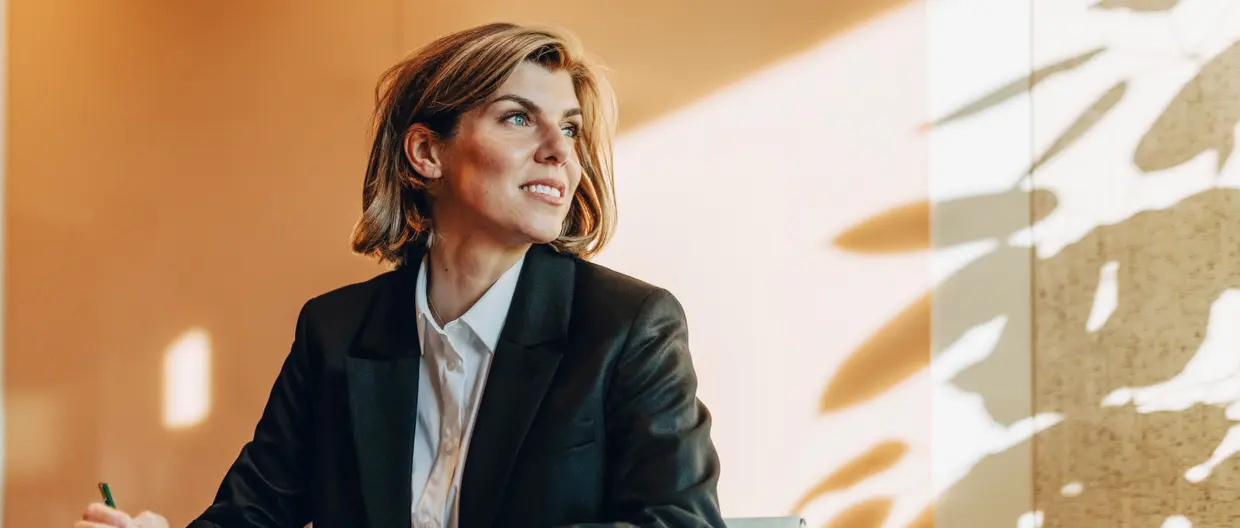 donna seduta al desk con lo sguardo rivolto verso l'esterno
