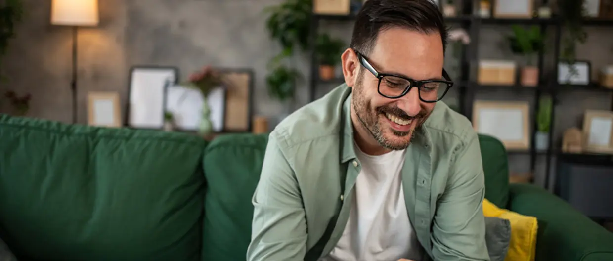 uomo sorridente che lavora sul tablet seduto in ambiente domestico