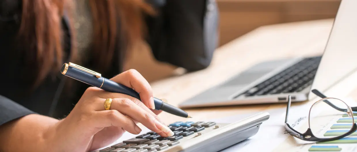 primo piano mani di donna che utilizza una calcolatrice con dei grafici