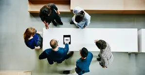 vista dall'alto di un gruppo di impiegati intorno ad un tavolo che consultano un tablet