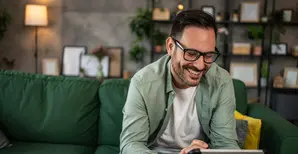 uomo sorridente che lavora sul tablet seduto in ambiente domestico
