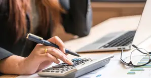 primo piano mani di donna che utilizza una calcolatrice con dei grafici
