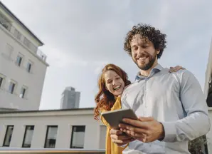 Due ragazzi sorridenti mentre guardano contenuto su tablet