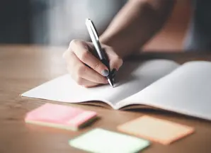 Dettaglio mano che scrive a penna su quaderno aperto