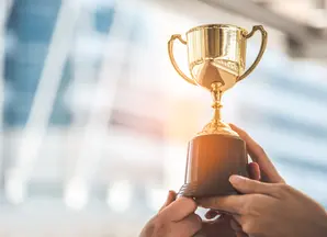 dettaglio di mani che sollevano al cielo piccolo trofeo