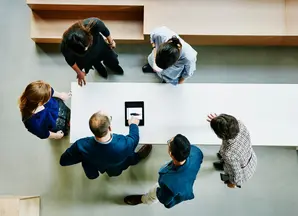 vista dall'alto di un gruppo di impiegati intorno ad un tavolo che consultano un tablet