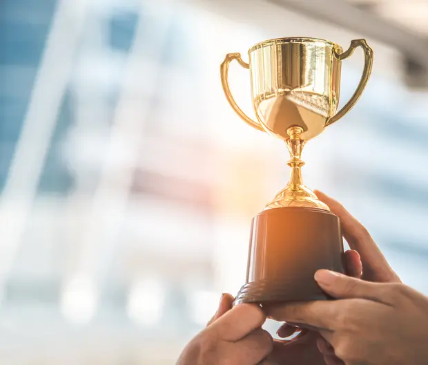 dettaglio di mani che sollevano al cielo piccolo trofeo