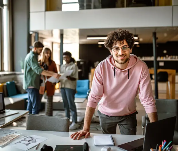 ragazzo sorridente in open space appoggiato al desk