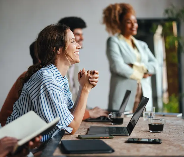 persone in ufficio che sorridono davanti ai propri laptop