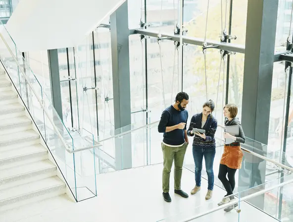 Gruppo di colleghi che parlando sulle scale di un palazzo con vetrate ampie