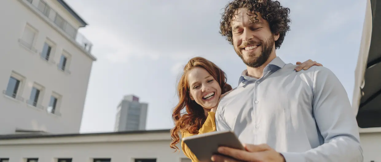 junges glückliches Paar mit Tablet unterwegs