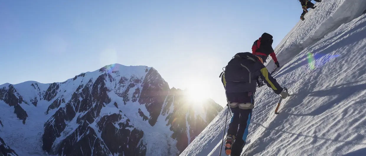 Un homme escalade une montagne enneigée avec deux autres