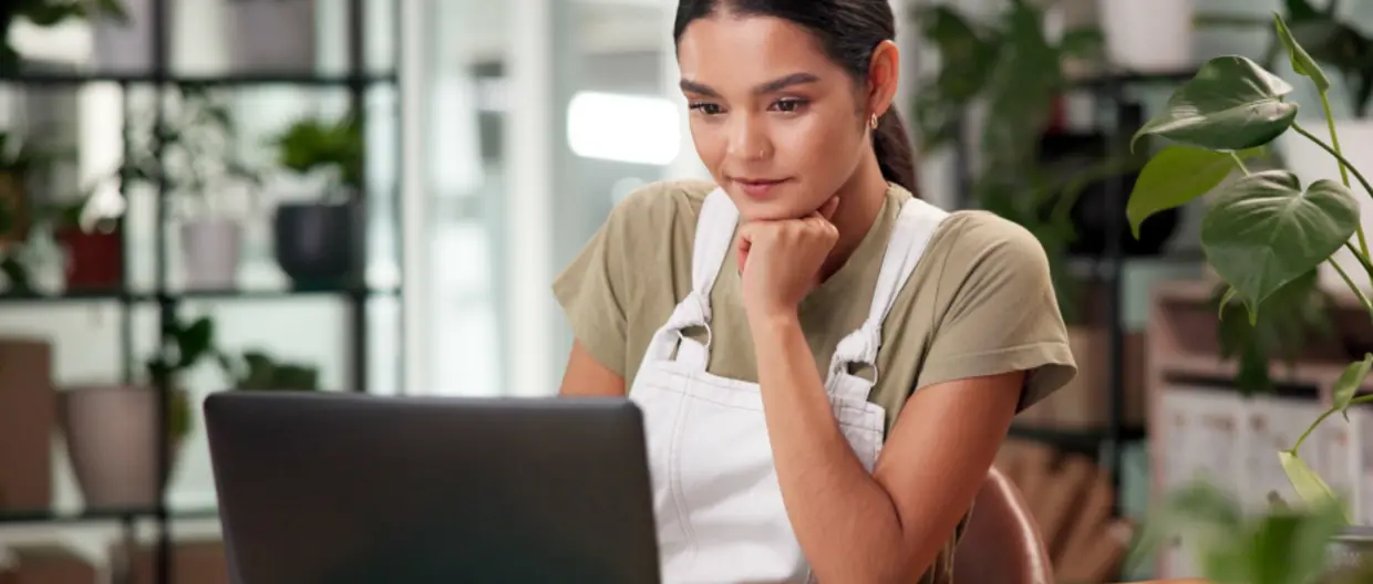 ragazza seduta al desk che guarda schermo laptop