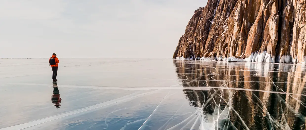 Photographer on the background of a rocky cape on Lake Baikal in winter 2