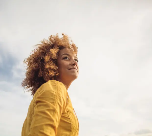 Woman in yellow top with grey clouds in background