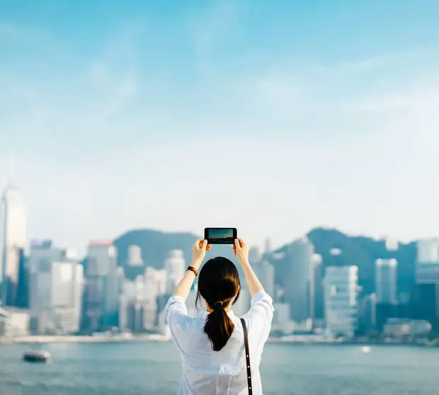 A woman capturing a photo of Hong Kong city