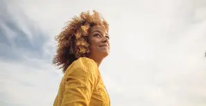 Woman in yellow top with grey clouds in background