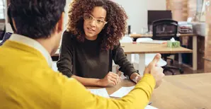 Woman sitting at a table talking to another person