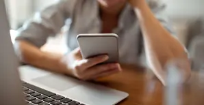 Une femme sur son téléphone devant son ordinateur
