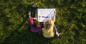 boy_and_girl_on_grass_experimenting_and_drawing_sustainable_energy_solutions