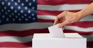 Hand hält Wahlzettel, die US-Flagge im Hintergrund