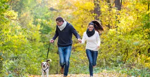 Un uomo e una donna corrono nel parco insieme al loro cane