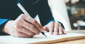 Une homme écrit dans un cahier