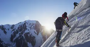 Un homme escalade une montagne enneigée avec deux autres