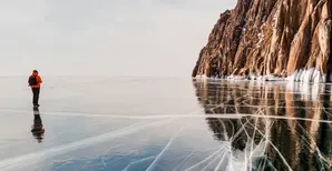 Photographer on the background of a rocky cape on Lake Baikal in winter 2