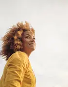 Woman in yellow top with grey clouds in background