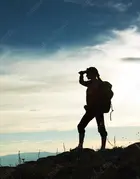 A silhouette of a woman looking at mountains in the distance