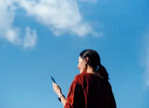 Woman on phone with blue sky in background