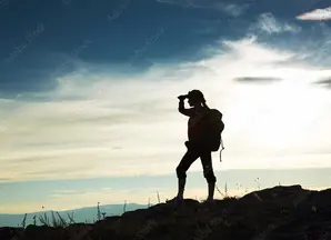 A silhouette of a woman looking at mountains in the distance