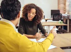 Woman sitting at a table talking to another person