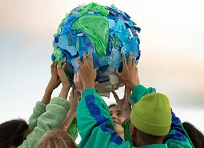 Kinder mit Weltkugel aus Plastikabfall