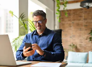 man at home looking at his phone smiling