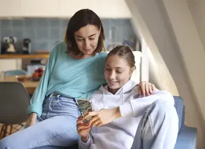 Une mère et sa fille regardent un téléphone