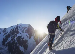 Un homme escalade une montagne enneigée avec deux autres