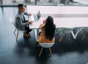 foto dall'alto di due persone che parlano tra loro davanti ad un pc