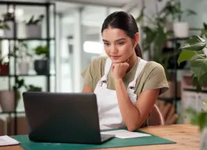 ragazza seduta al desk che guarda schermo laptop