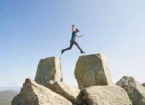 ragazzo che salta su una roccia