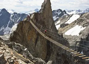 Hiker on wood bridge in between mountains