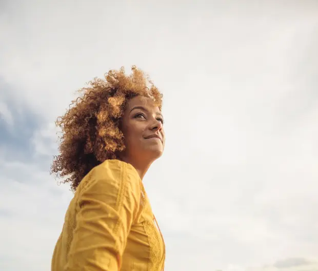Woman in yellow top with grey clouds in background