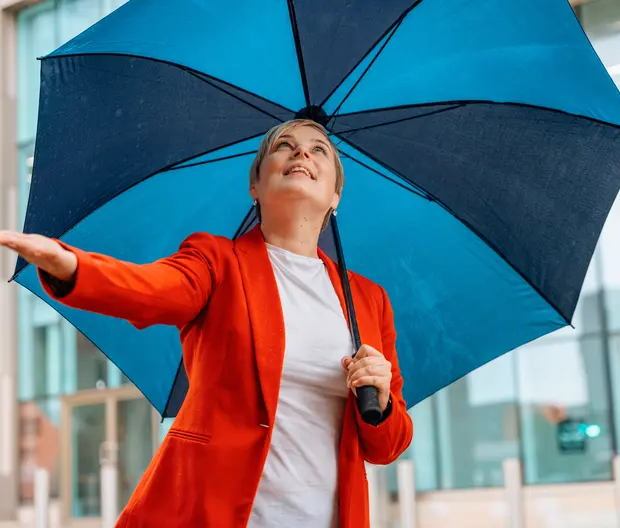 woman with a red jacket under a blue umbrella