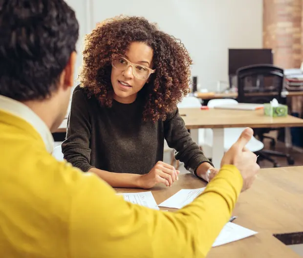 Woman sitting at a table talking to another person