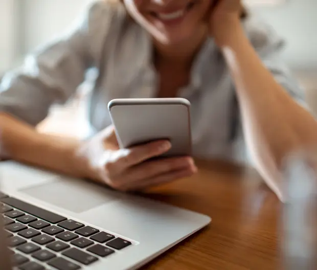 Une femme sur son téléphone devant son ordinateur