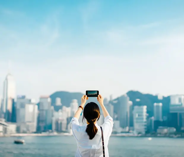 A woman capturing a photo of Hong Kong city