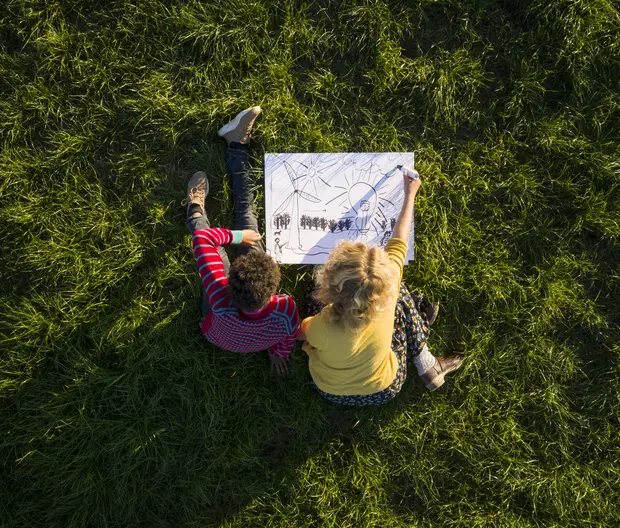 boy_and_girl_on_grass_experimenting_and_drawing_sustainable_energy_solutions
