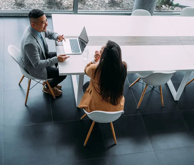foto dall'alto di due persone che parlano tra loro davanti ad un pc