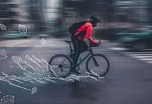 immagine di ciclista con sfondo città sfocato e illustrazioni poligonali